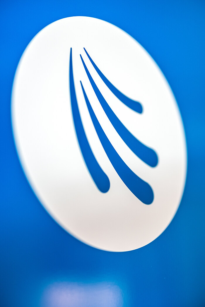 Logo der Arztpraxis Dr. Markus Ruch in Triberg: Weißes Logo mit stilisierten geschwungenen Linien auf einem blauen Hintergrund. Die Linien verlaufen in abgerundeter Form und vermitteln einen Eindruck von Bewegung und Dynamik.